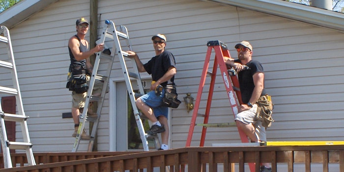 contractor crew replacing siding on ladders