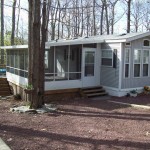 large screen room attached to mobile home in the woods